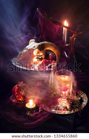 Mystic still life with a ram's head, candles, pomergranate, fire and smoke. Witchcraft vertical still life for halloween. 
