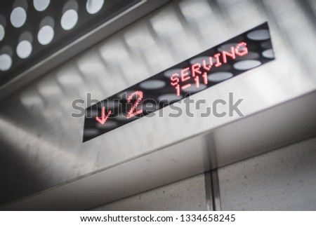 Red LED in a metallic elevator display showing the elevator going downward with modern design