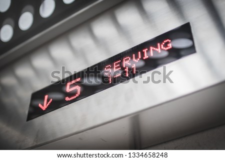 Red LED in a metallic elevator display showing the elevator going downward with modern design