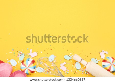 Easter rabbits and eggs with kitchen utensil on yellow background