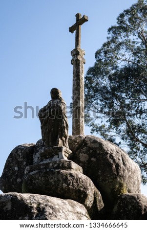 Antique stone cross and statue of St. James the Apostle on big granite rocks with blue sky. Pilgrimage, Padron, Spain