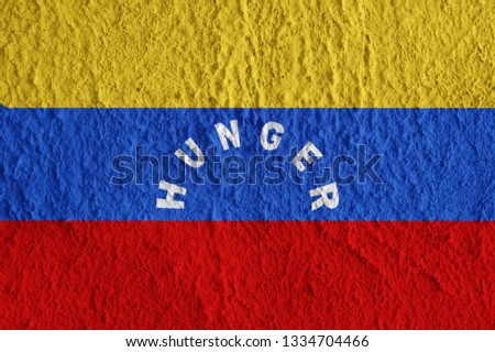 Venezuela flag with the inscription HUNGER on the concrete surface. Conceptual grunge wallpaper for installation and design.