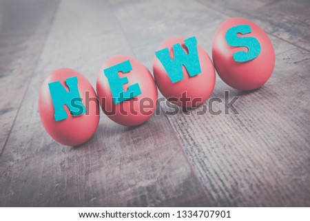 News factory: four eggs with "news" word on wooden background