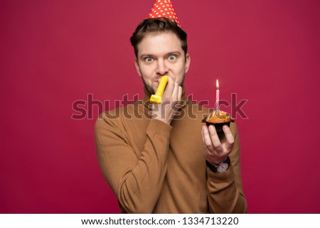 People, joy, fun and happiness concept. Relaxed happy birthday guy looking cheerful, smiling happily, posing for picture, holding cupcake
