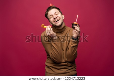 People, joy, fun and happiness concept. Relaxed happy birthday guy looking cheerful, smiling happily, posing for picture, holding cupcake