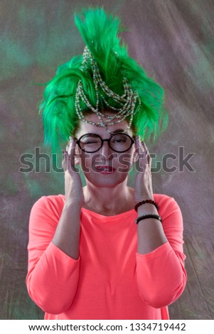 caucasian girl in green dress and with green hair is preparing for holidays. Suit of the teacher of primary classes. The concept of happy holidays and good mood.