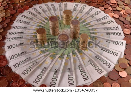 MONEY STACKED COINS  ON 100 EUROS BANKNOTES SURROUNDED WITH EURO COINS 