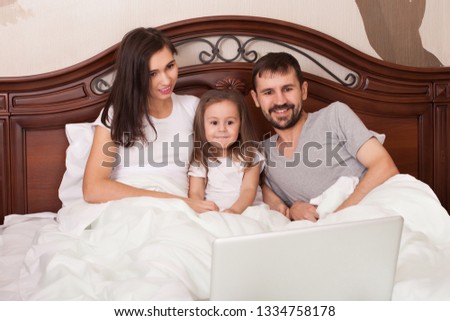 Happy family watching movie in bed