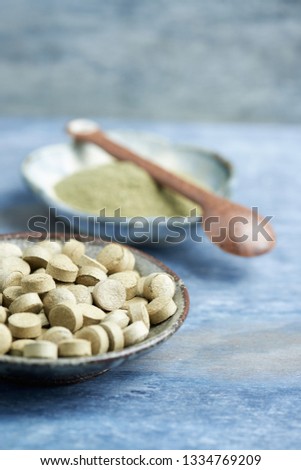 Bio Green BARLEY GRASS tablets and powder. Concept for a healthy dietary supplementation. Rustic wooden background. Copy space. 