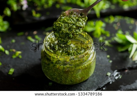 pesto sauce in a spoon, jar with pesto sauce Royalty-Free Stock Photo #1334789186
