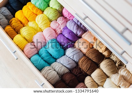 Knitting accessories. Colorful multicolored skeins of yarn in the dresser. Storage.Yellow, blue, pink, milk, beige, gray, purple, lilac yarn.