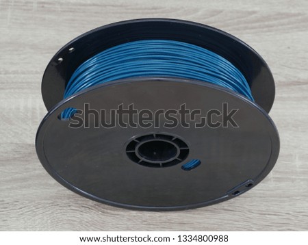 Blue PLA plastic on black spool