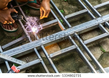 Hands of a man welding a steel construction with an electric welder