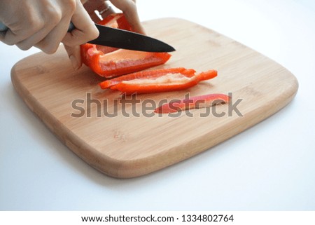Female cook chopping fresh vegetables on wooden board: red and yellow bell pepper, green onions, chili, garlic, carrot and spinach