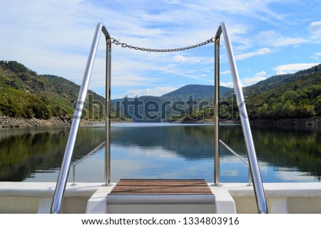 Close-up of recreational boat ladder sailing on the Sil river with the mountain reflected in the water in the background, in Galicia, Spain.