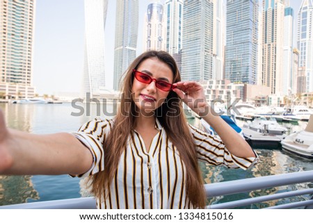 Young woman tourist laughing and taking selfie photo in Dubai Marina in United Arab Emirates.