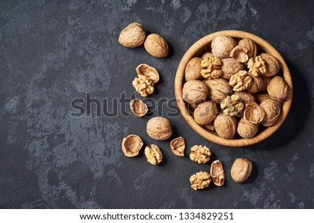 Walnut in wooden bowl on black background with copy space.Top view. Wooden plate with walnut on black background. Space for text Royalty-Free Stock Photo #1334829251