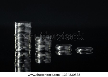 Close up of silver coin stack money on black background table with mirror reflection