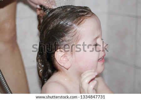 A cute little girl is showering and showing her tears of shampoo that bites her eyes.-Image