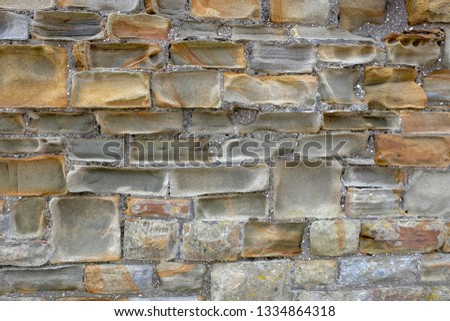 Sandstone wall that's has been weathered and eroded leaving abstract shapes and warm colours
