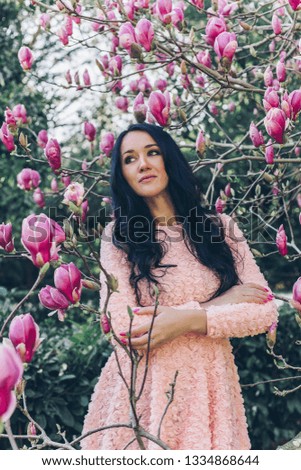 a woman in a pink dress is standing in magnolia