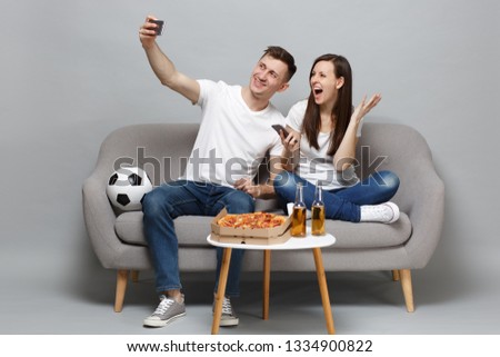 Fun couple woman man football fans cheer up support favorite team doing selfie shot on mobile phone isolated on grey wall background in studio. People emotions, sport family leisure lifestyle concept