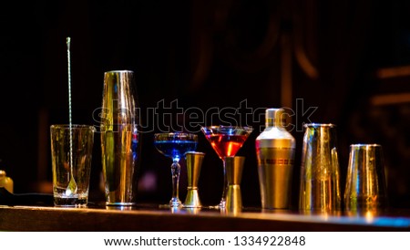 Set of bar or pub accessories with a martini cocktail shaker arranged in a neat line on a black background