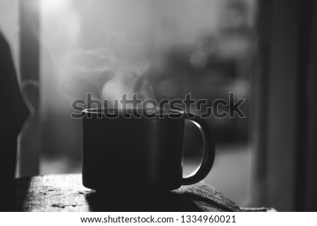 Steam of hot water in a cup with smoke over dark background.