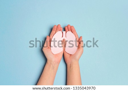 Women's hands hold a lungs symbol on blue background. World Tuberculosis Day. Healthcare, medicine, hospital,  diagnostic, internal donor organ.