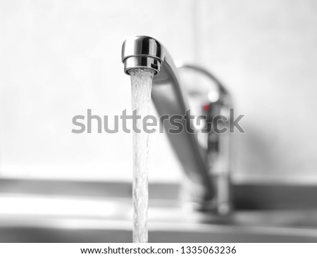 Water runs from a metal water tap. Close up. Royalty-Free Stock Photo #1335063236