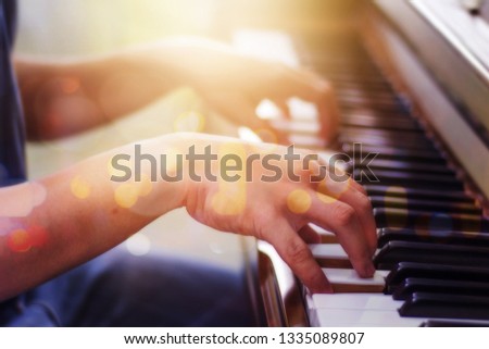 close up of a man hands plays on piano keys against window light and bokeh, Music background with copy space