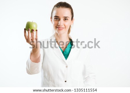 Doctor promoting healthy life. Young nurse holds an apple. 