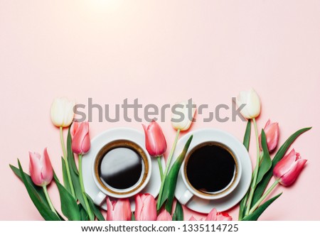 Minimalistc picture of cup of coffee and beautiful pink and white tulips on blue background. Spring coffee concept. top view, flat lay. Copyspace for your text.