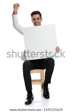seated happy elegant man celebtrates a win while showing blank board on white background