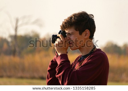 young boy with a retro camera doing photography on a summer day