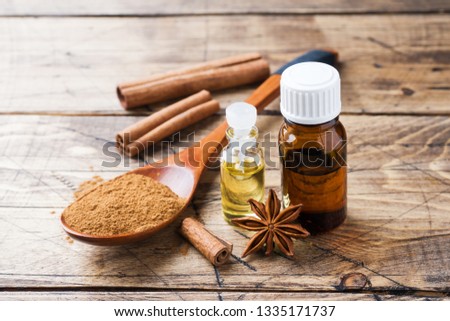 Essential aroma oil with cinnamon and star anise on wooden background. Selective focus