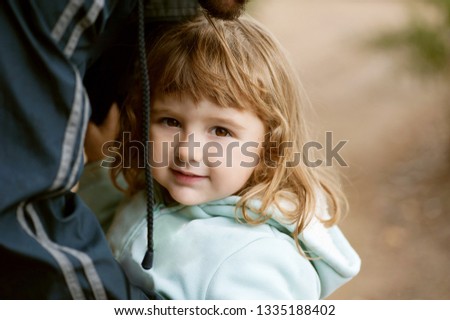 portrait of smiling little girl, small cheerful girl in coat holding to her father