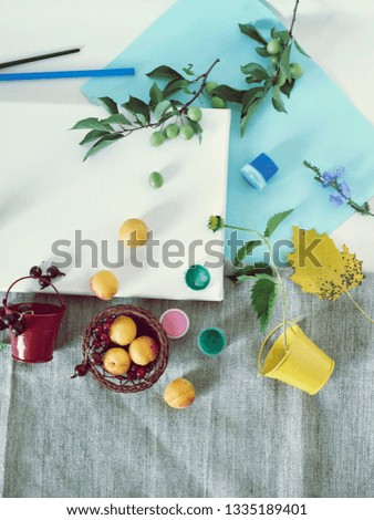 Art materials, paints, brushes, colored pencils, white canvas, flowers and fruits on a light background, top view, concept of summer, creativity, study, holidays, decorative seasonal composition