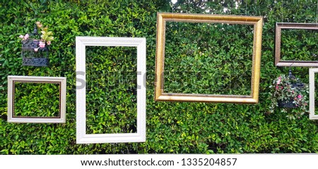 Picture frame and flower pot hanging on green leaves wall for decoration festival, event or wedding party. Decorated, Background, Object and Nature wallpaper concept.