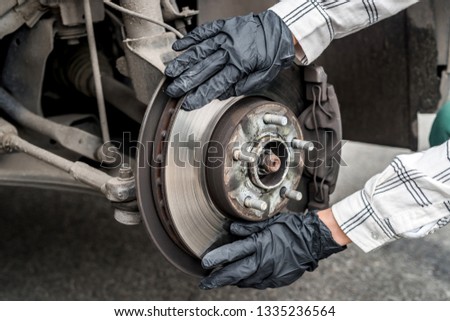 Brake disk with worker's hands in gloves close up