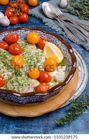 Baked sea fish fillet with vegetables and green sauce on wooden background. Selective focus.
