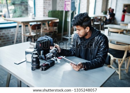 Smart young asian man photographer working with tablet during sitting at cafe.