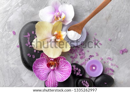 Spa stones, orchid flowers and sea salt on grey background