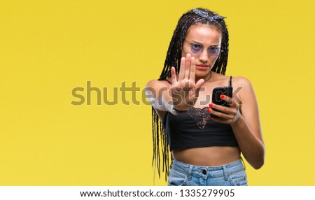Young braided hair african american with birth mark using smartphone over isolated background with open hand doing stop sign with serious and confident expression, defense gesture