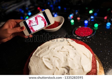 Woman in kitchen following recipe on her smartphone. Comparing result. Girl using her smartphone to take stylish pictures of food. Concept of daily blogging. 
