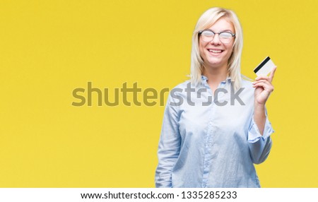 Young beautiful blonde business woman holding credit card over isolated background with a happy face standing and smiling with a confident smile showing teeth