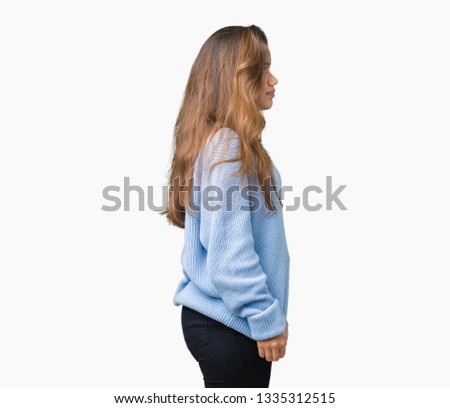 Young beautiful brunette woman wearing blue winter sweater over isolated background looking to side, relax profile pose with natural face with confident smile.