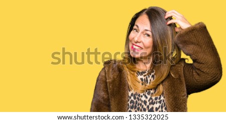 Beautiful middle age elegant woman wearing mink coat confuse and wonder about question. Uncertain with doubt, thinking with hand on head. Pensive concept.