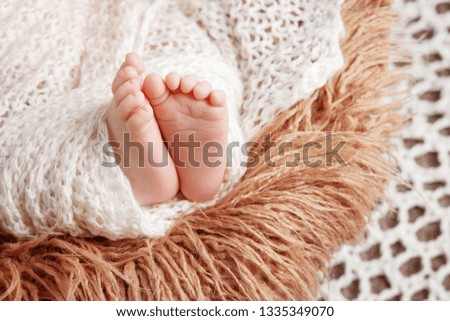 Newborn baby feet on knitted plaid. Closeup picture.