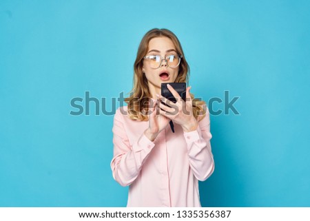Java woman in a pink shirt with a calculator in her hands in surprise looks blue background
